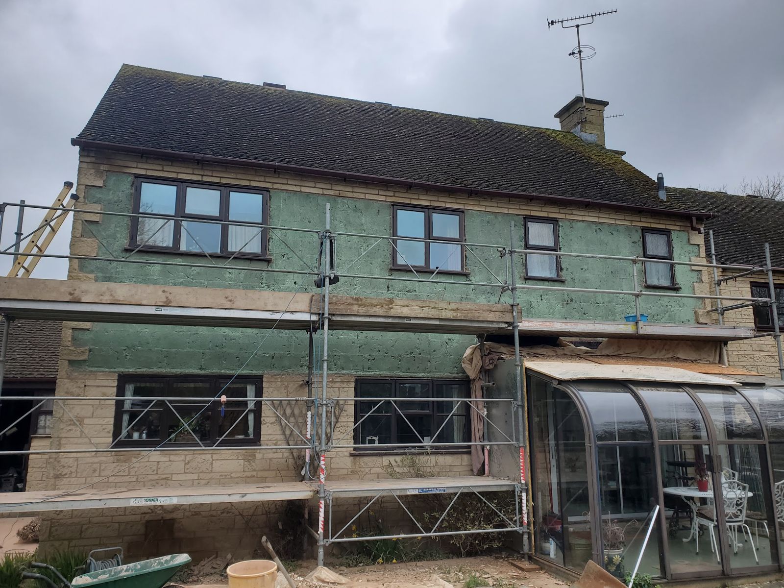 A stone house in scaffolding with insulation boards fixed ready for render