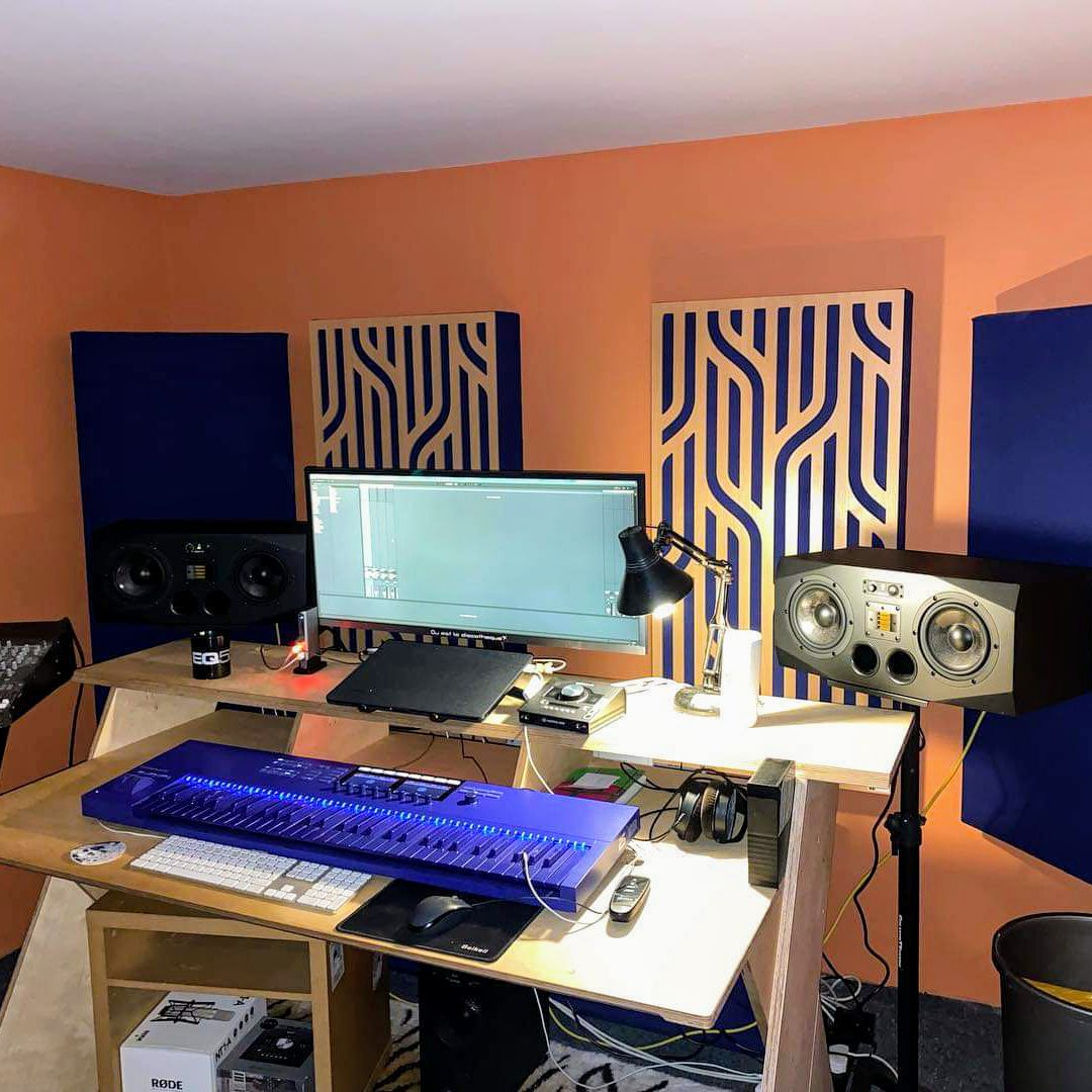 A music studio with orange walls, speakers and a mixing desk