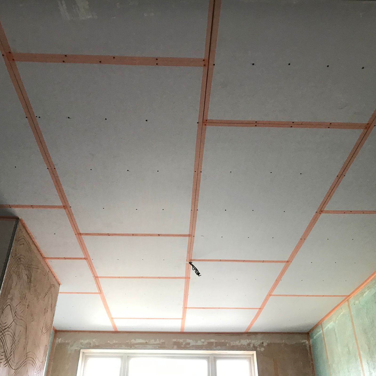 A ceiling boarded out with pink scrim tape over every joint