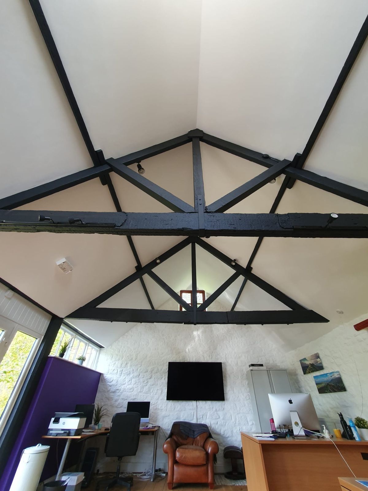 A barn conversion ceiling plastered between black trusses