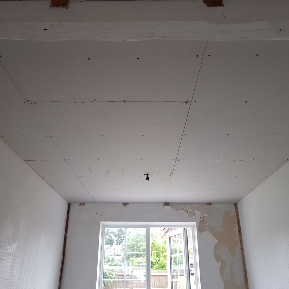 A ceiling overboarded with fresh plasterboard after the beams came out