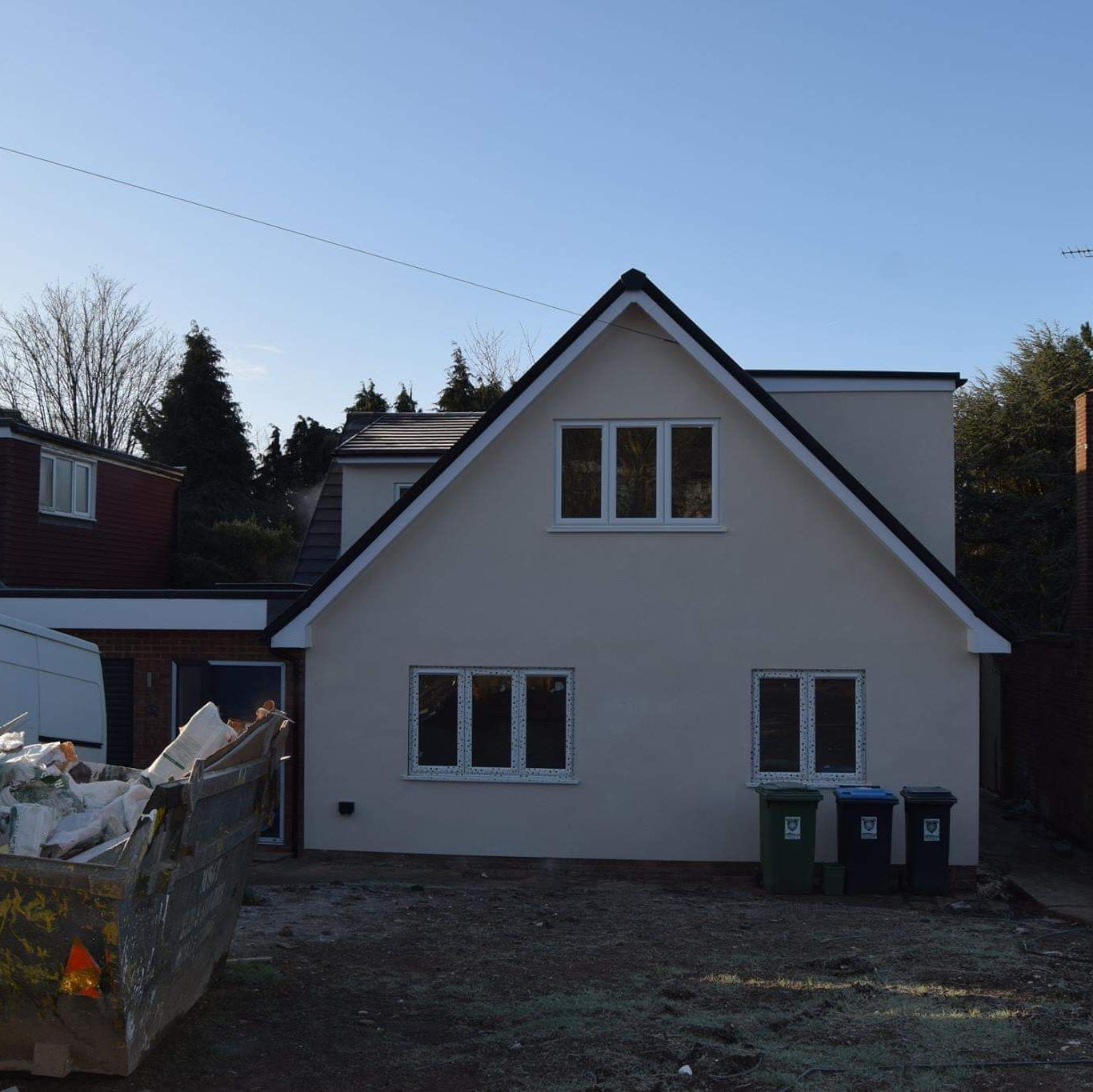 A rendered white house with a skip on the drive