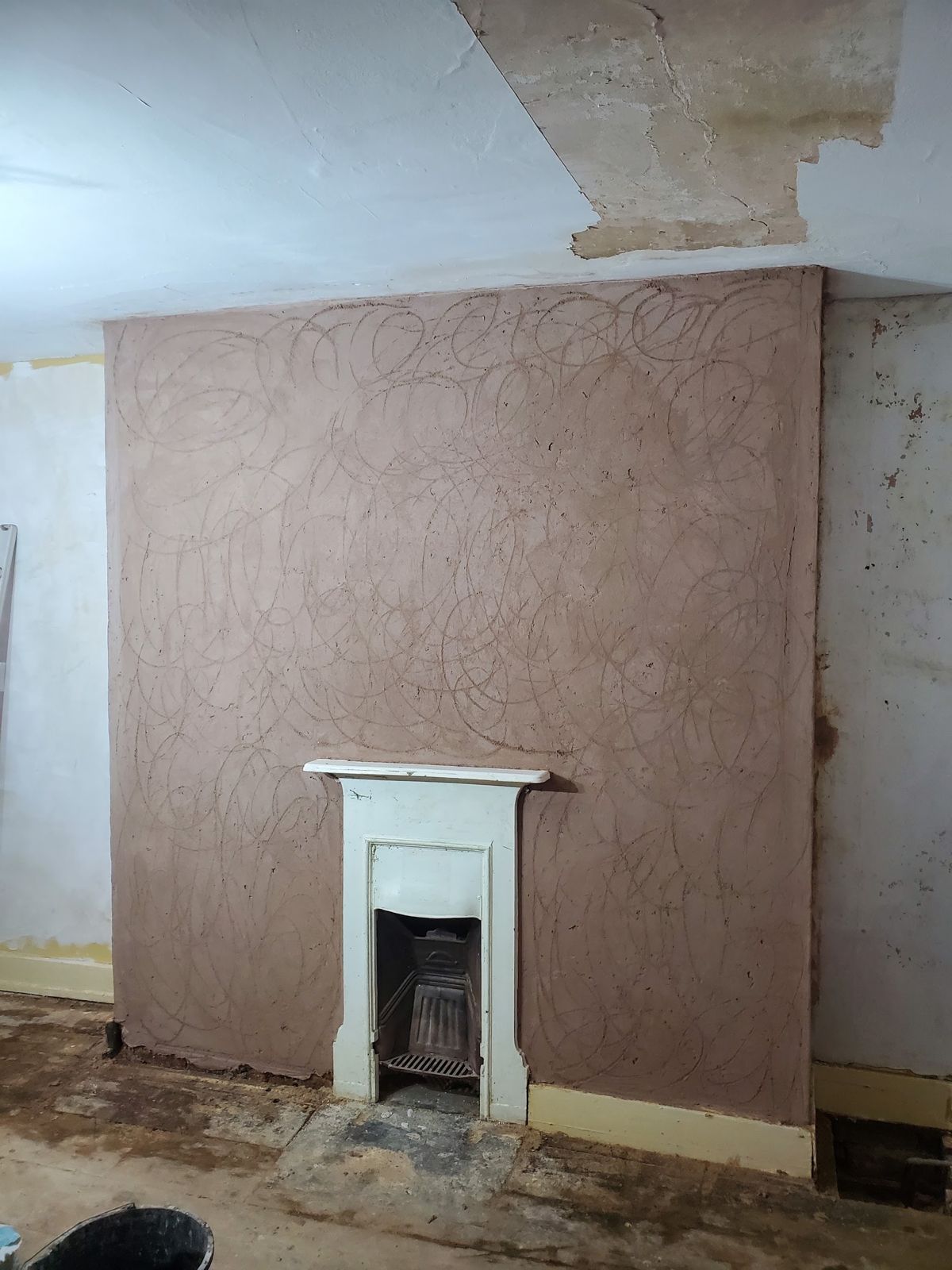A lime float coat on a chimney breast above a small fireplace in a Grade II listed building