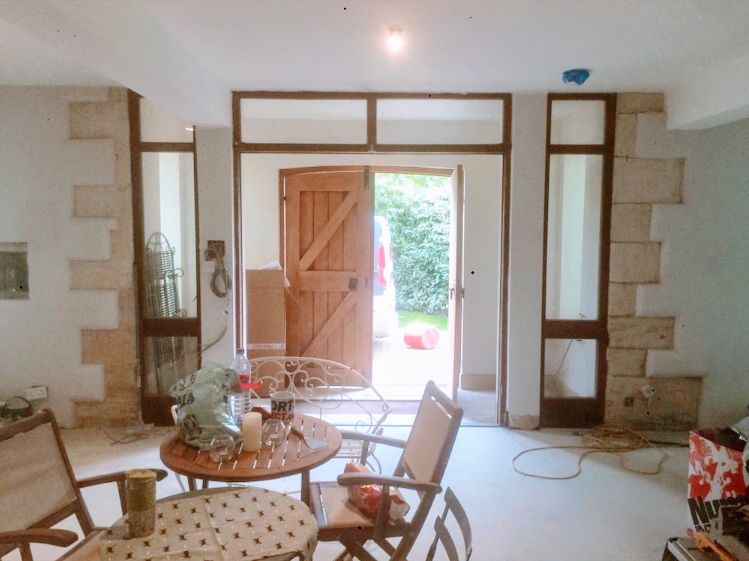 A hallway with a stone and plaster feature around a glazed oak door