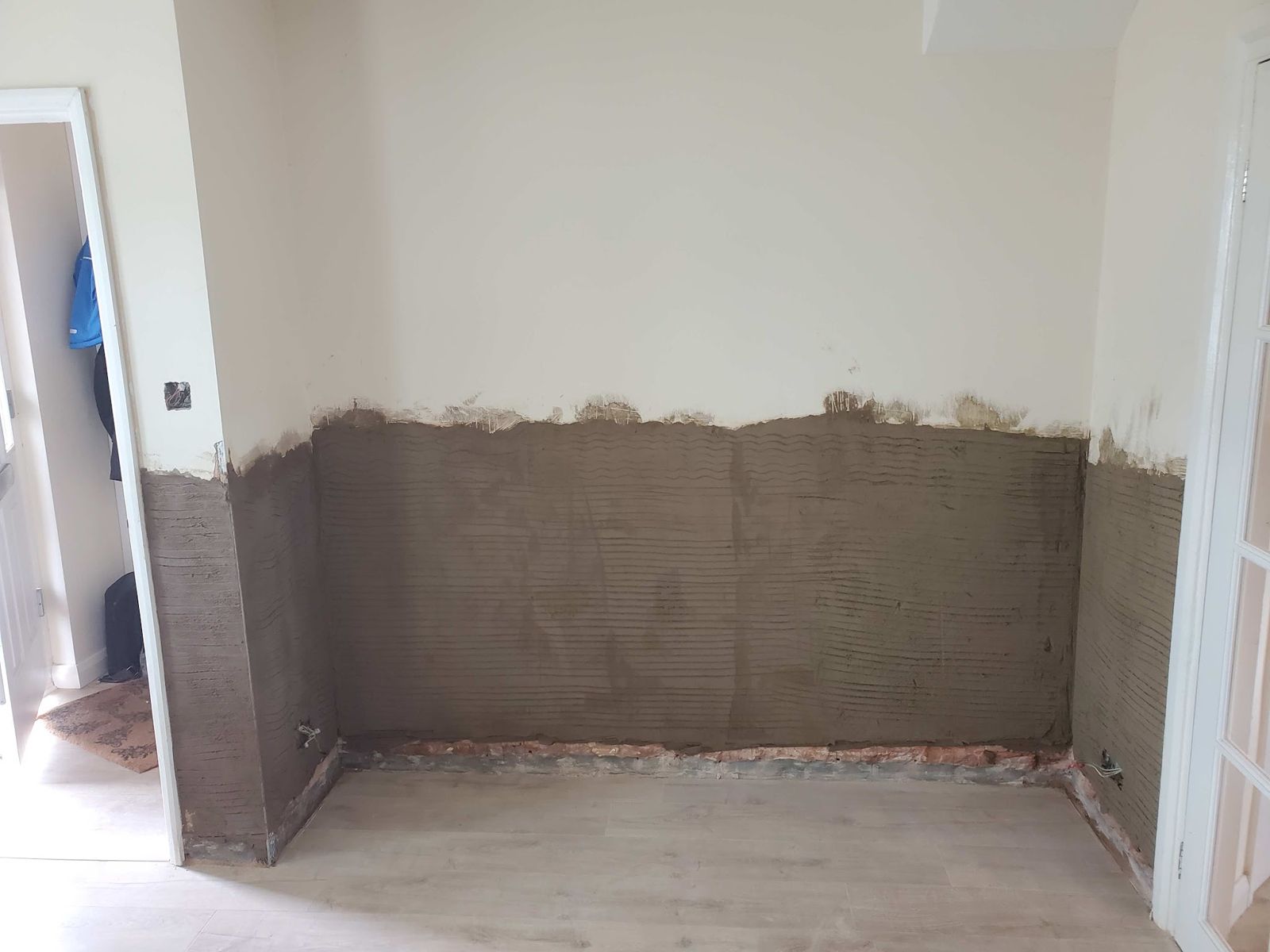 Render with a salt inhibiting additive on the lower walls of a room after a damp proof course